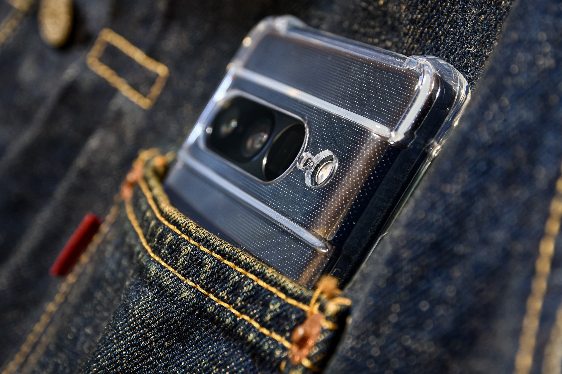 Smartphone with a clear case placed in the pocket of a denim jacket, highlighting the rear camera module.