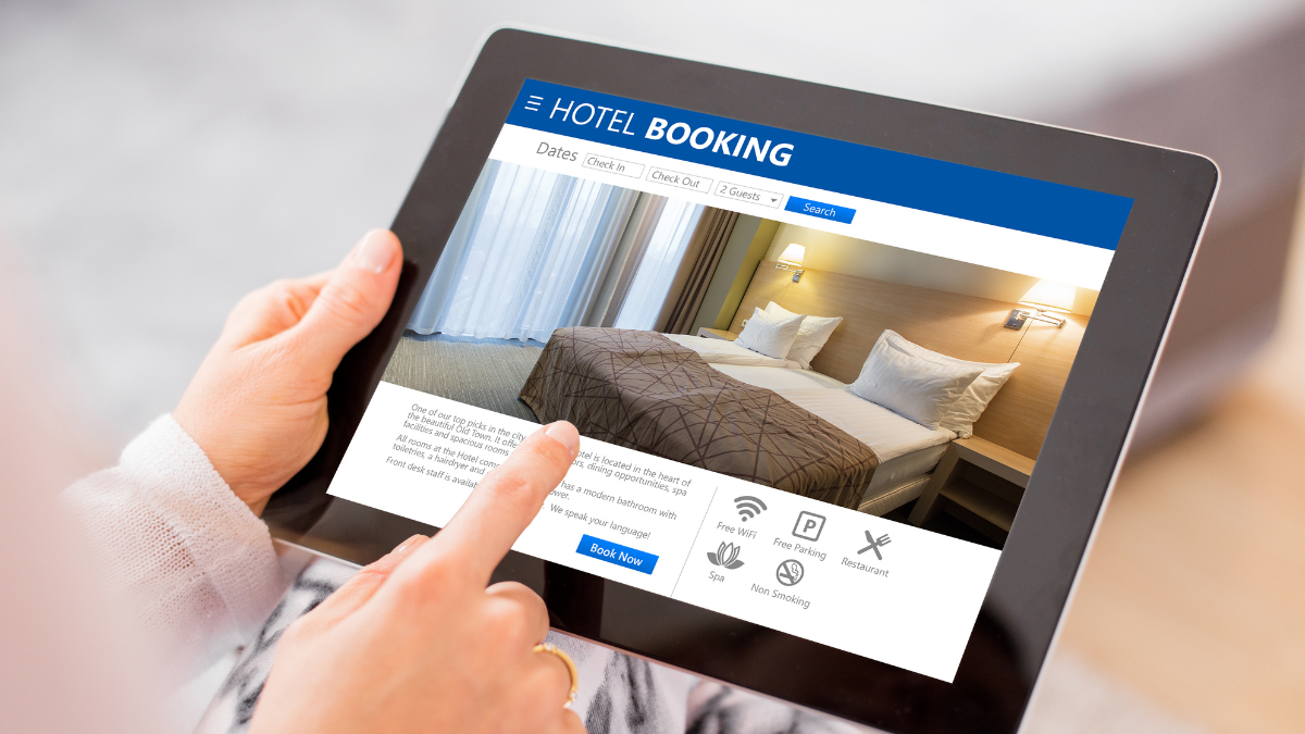 Person booking a hotel room online using a tablet showing hotel booking website